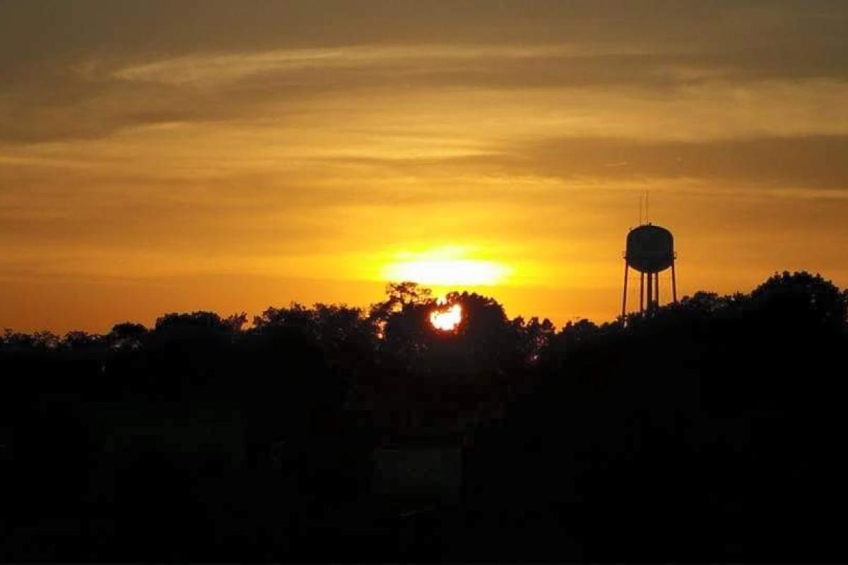 Sunset in a water tower town Beebe AR heart framed in trees 
