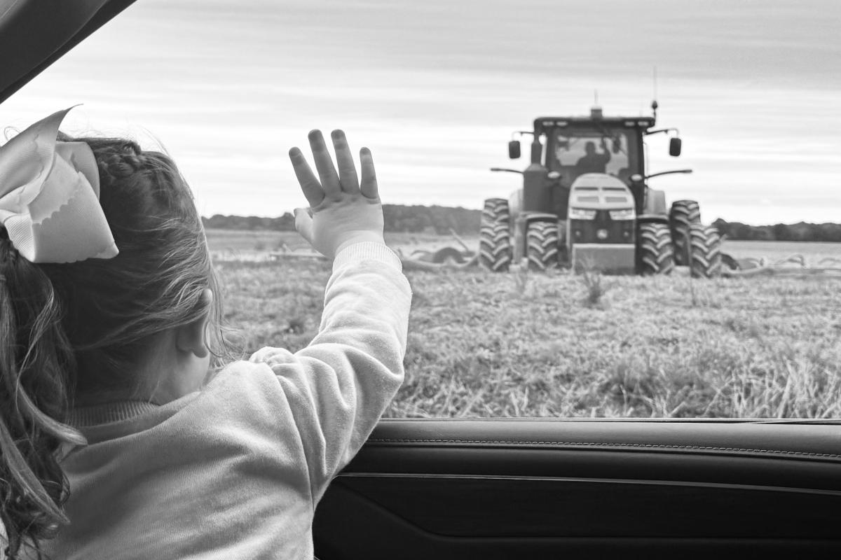 Madilyn, granddaughter of Michael Knoll, waving at him on the tractor after delivering field lunch