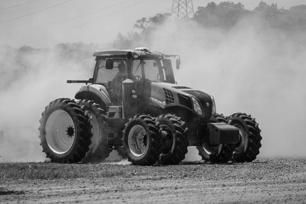 Black and white picture of farmer discing field